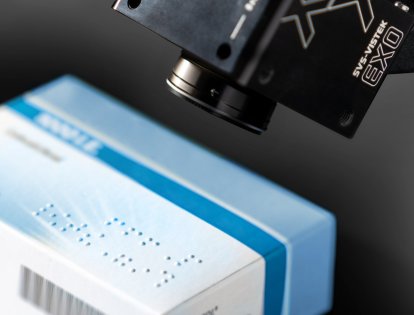 Schwarze Industriekamera der EXO-Serie von SVS-Vistek schaut auf eine blau-weiße Arzneiverpackung mit Braille-Schrift