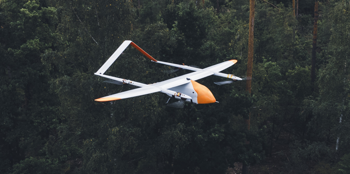 Weiß-orange-farbene Evolonic-Drohne fliegt über Wald um Brände frühzeitig zu erkennen